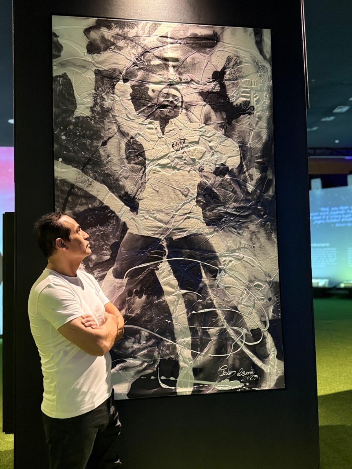O artista observa uma pintura monumental dedicada a Pelé no espaço expositivo.
